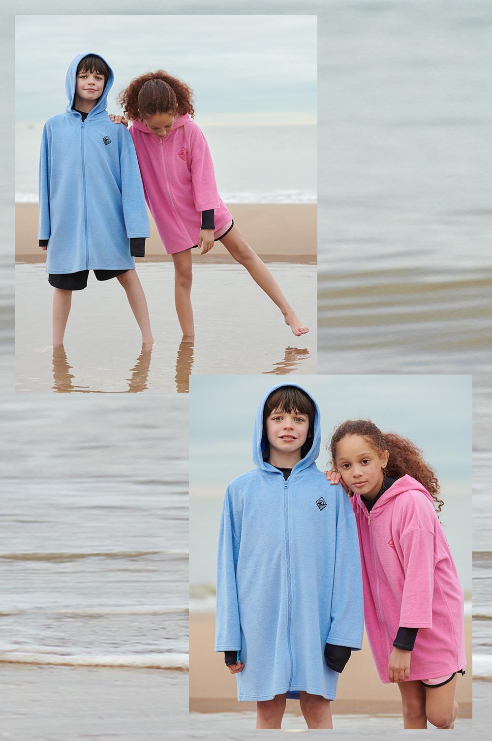 Enfants portant des ponchos de surf zippés bleus et roses