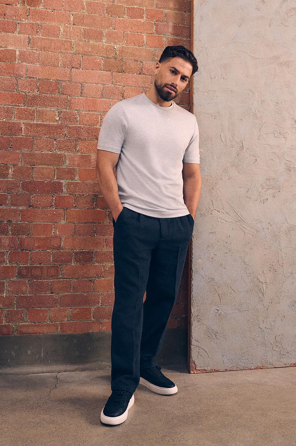 Kem indossa una T-shirt slim fit grigia, pantaloni e scarpe da ginnastica