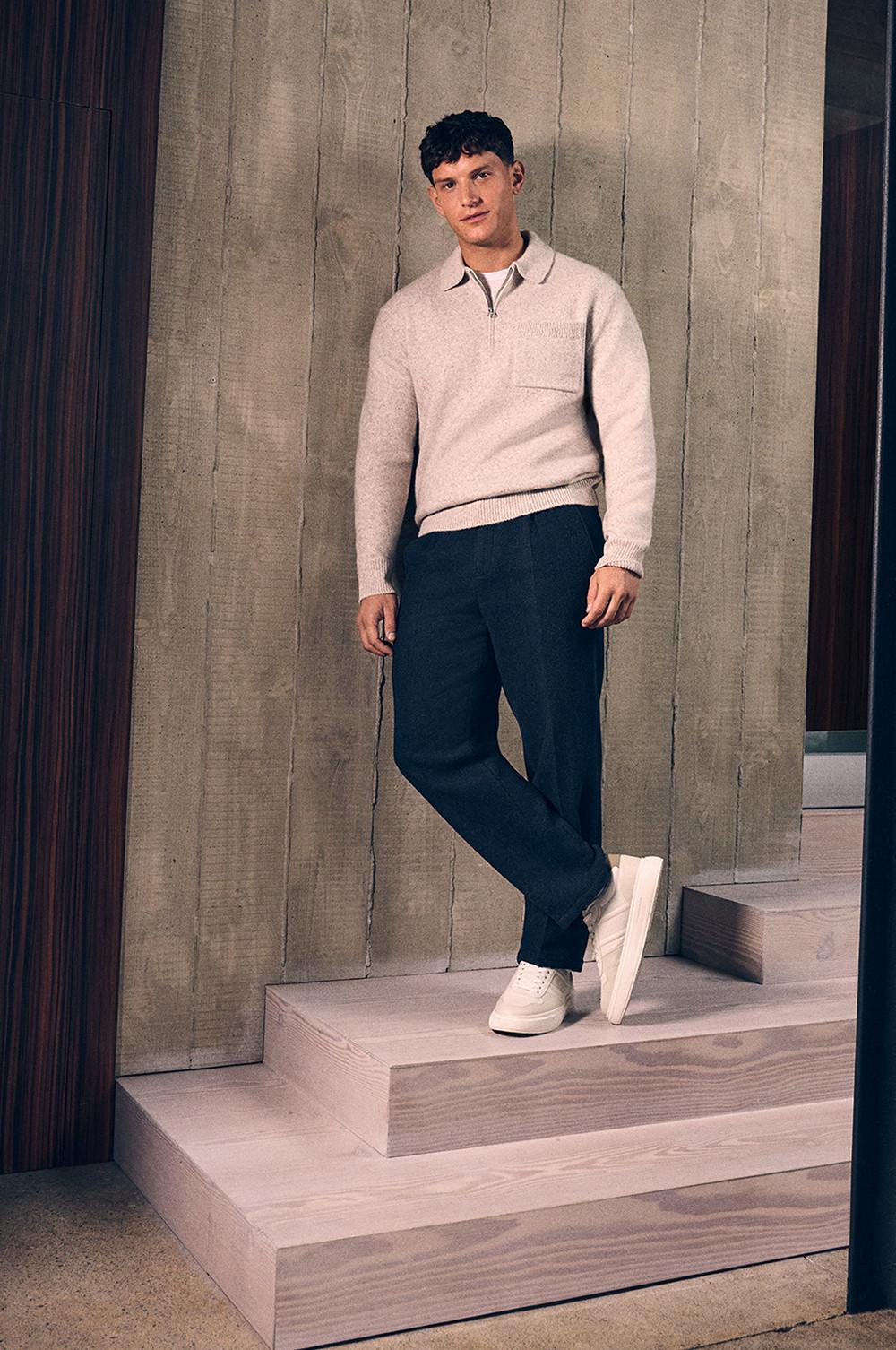 Model wears half zipped jumper and smart dark trousers