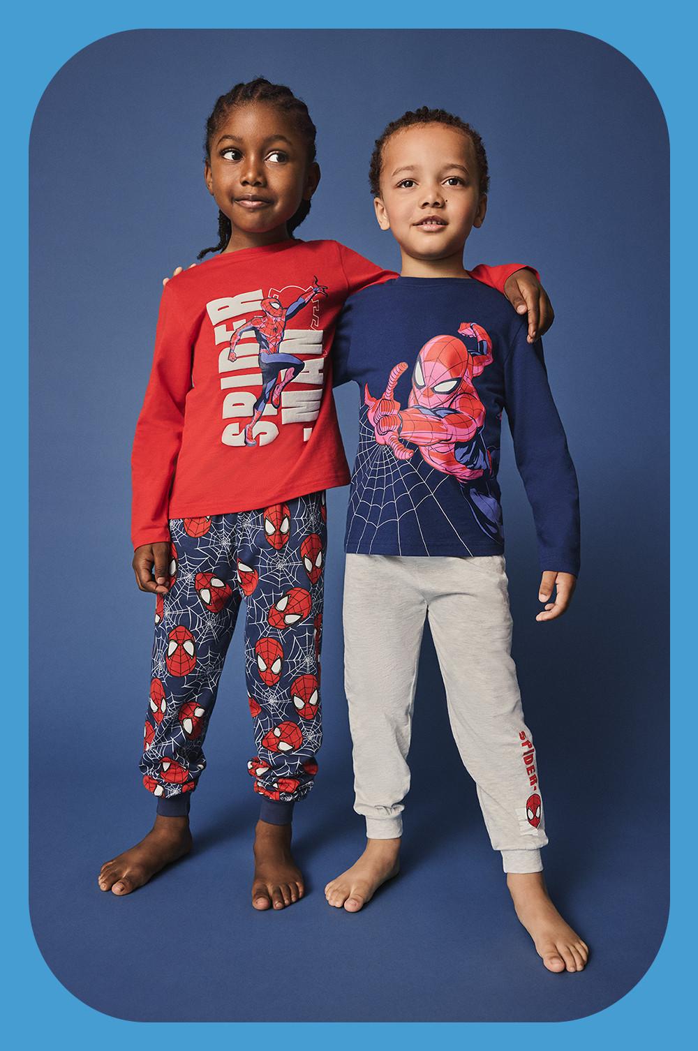 Due bambini che indossano un pigiama a maniche lunghe in versione blu e rossa con pantaloni stampati