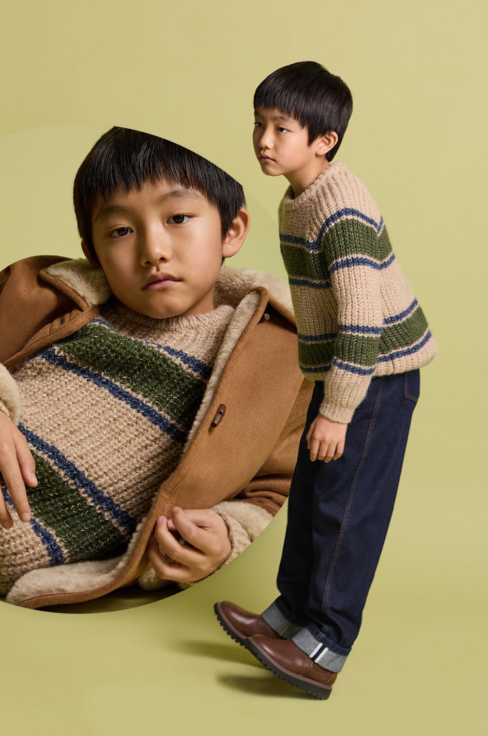 Children wearing striped knit jumpers with a camel coat, denim trousers and brown shoes.
