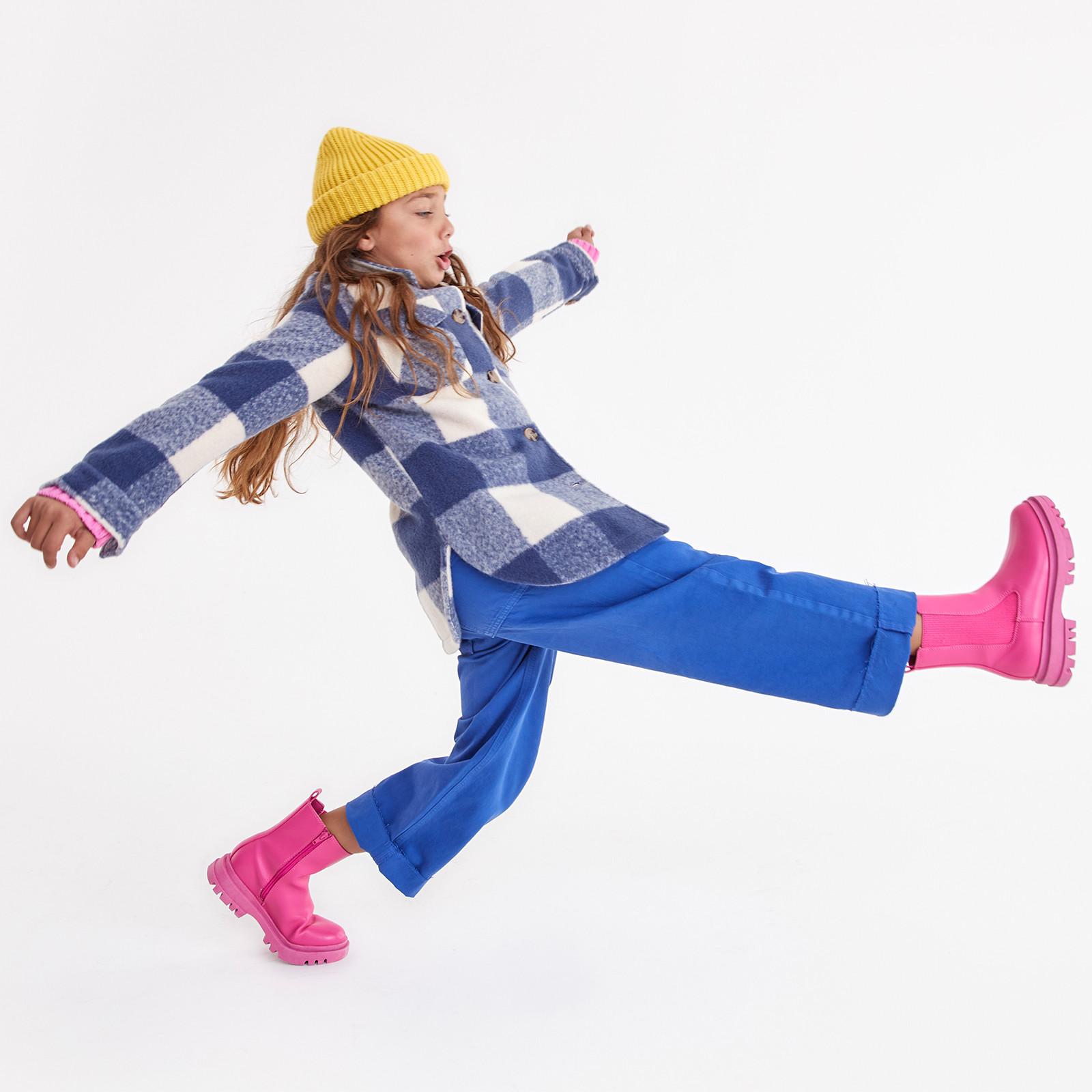 Child wears blue shacket and trousers, paired with pink boots and a yellow beanie