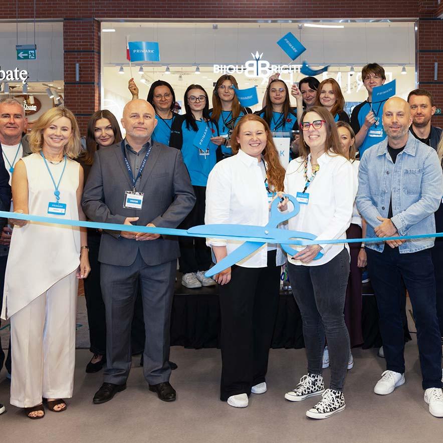 People hold oversized blue scissors to cut a ribbon at a Primark store opening.