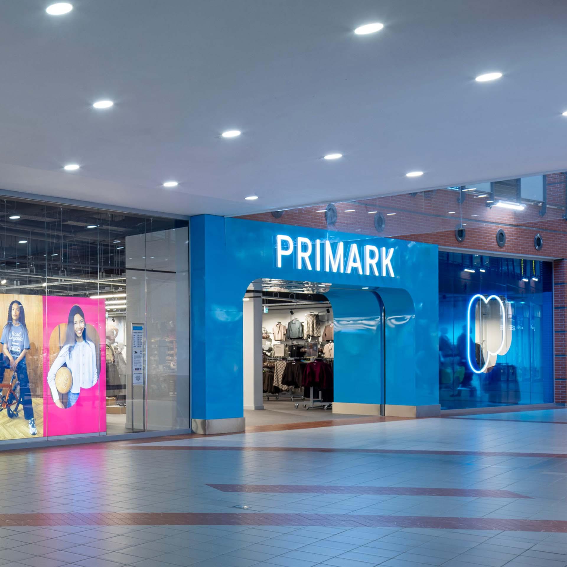 Primark store in a shopping mall with a bright blue facade, arched entrance and glass windows.