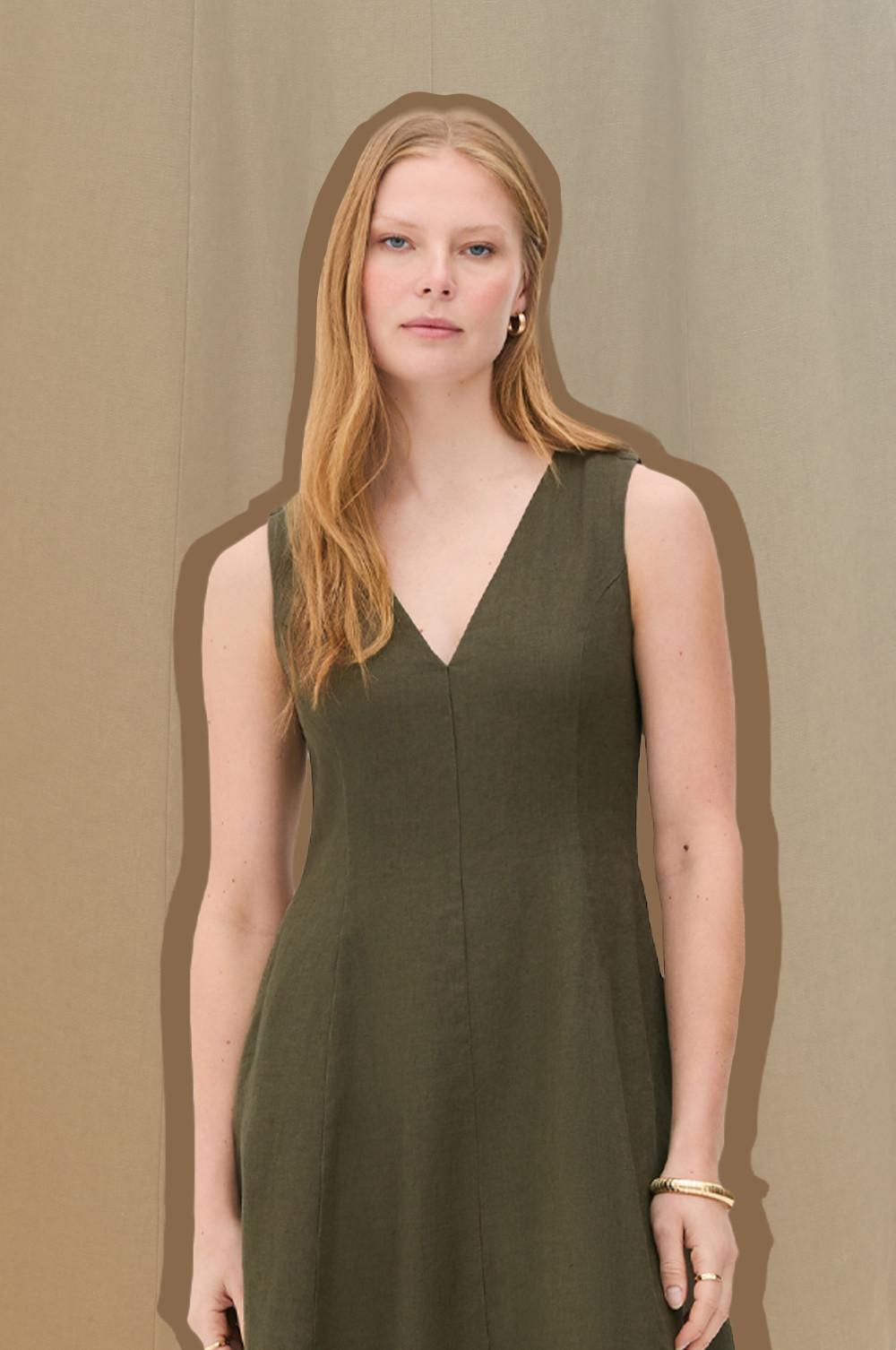 Sleeveless olive dress with V-neck worn by model. Model accessorized with gold-toned bracelet.