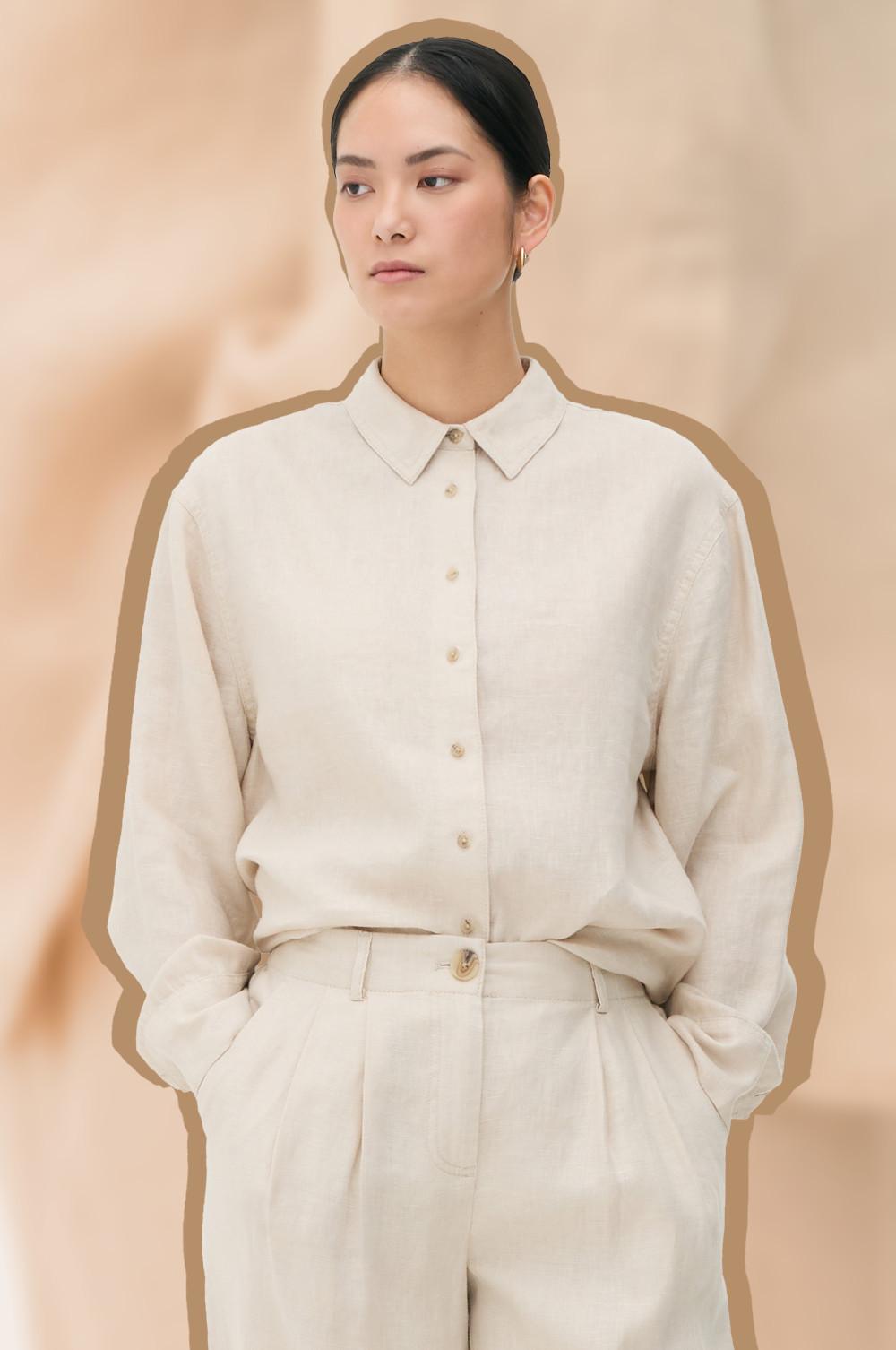 Person wearing a beige button-up shirt and trousers with hands in pockets.