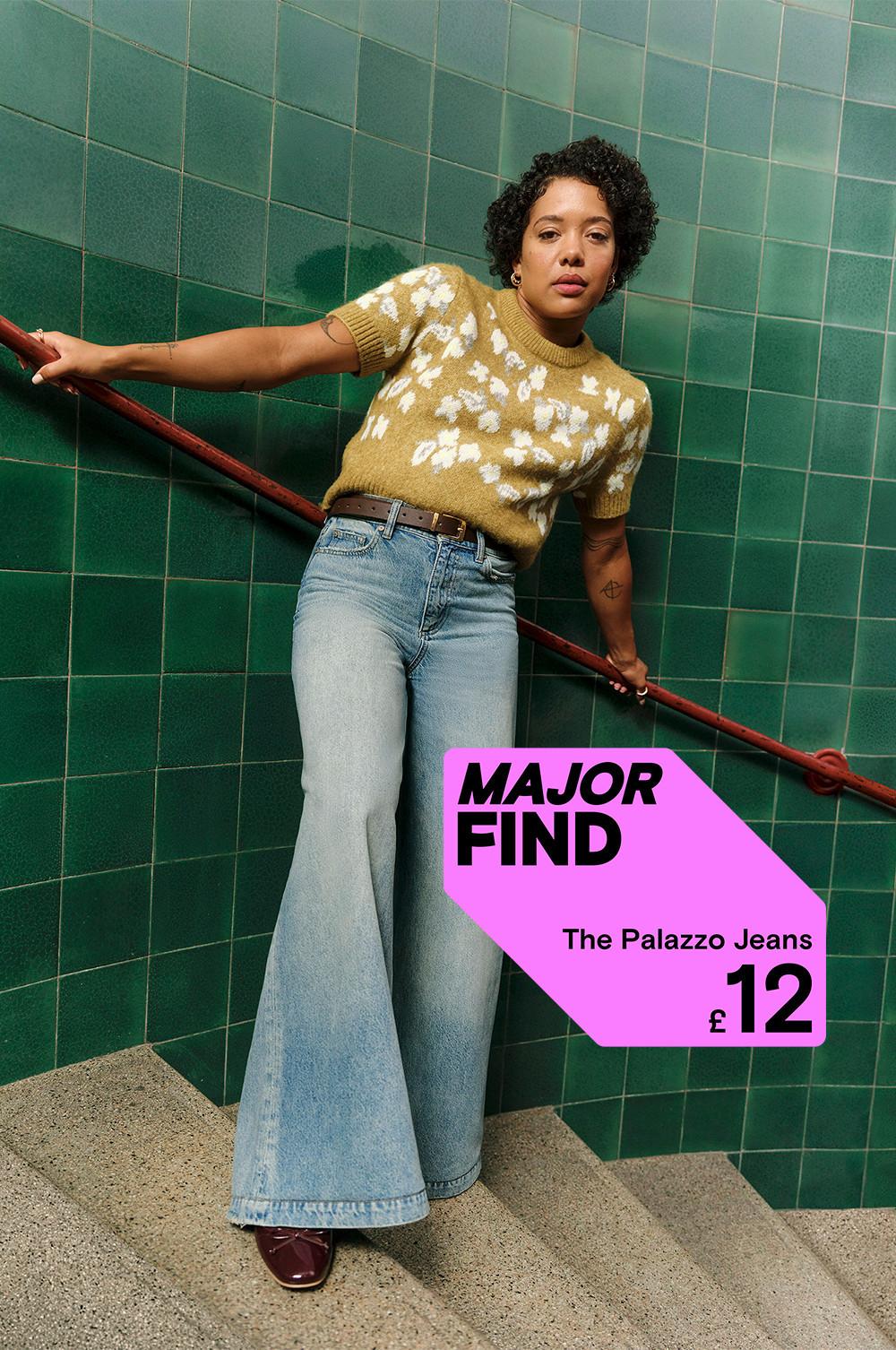 Wide-leg Palazzo jeans priced at £12, paired with mustard floral jumper against green tiled wall.