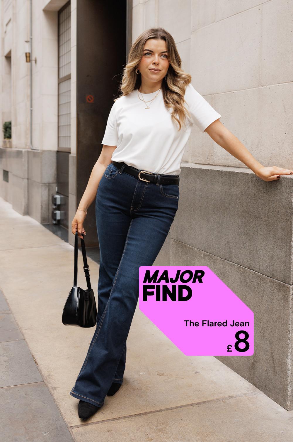 Person wearing flared jeans with white t-shirt and black handbag. Pink tag shows "MAJOR FIND The Flared Jean £8".