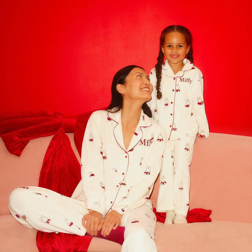 Modelle, una adulta e una bambina, che indossano trench corti in coordinato con maglie da rugby a righe coordinate sullo sfondo.