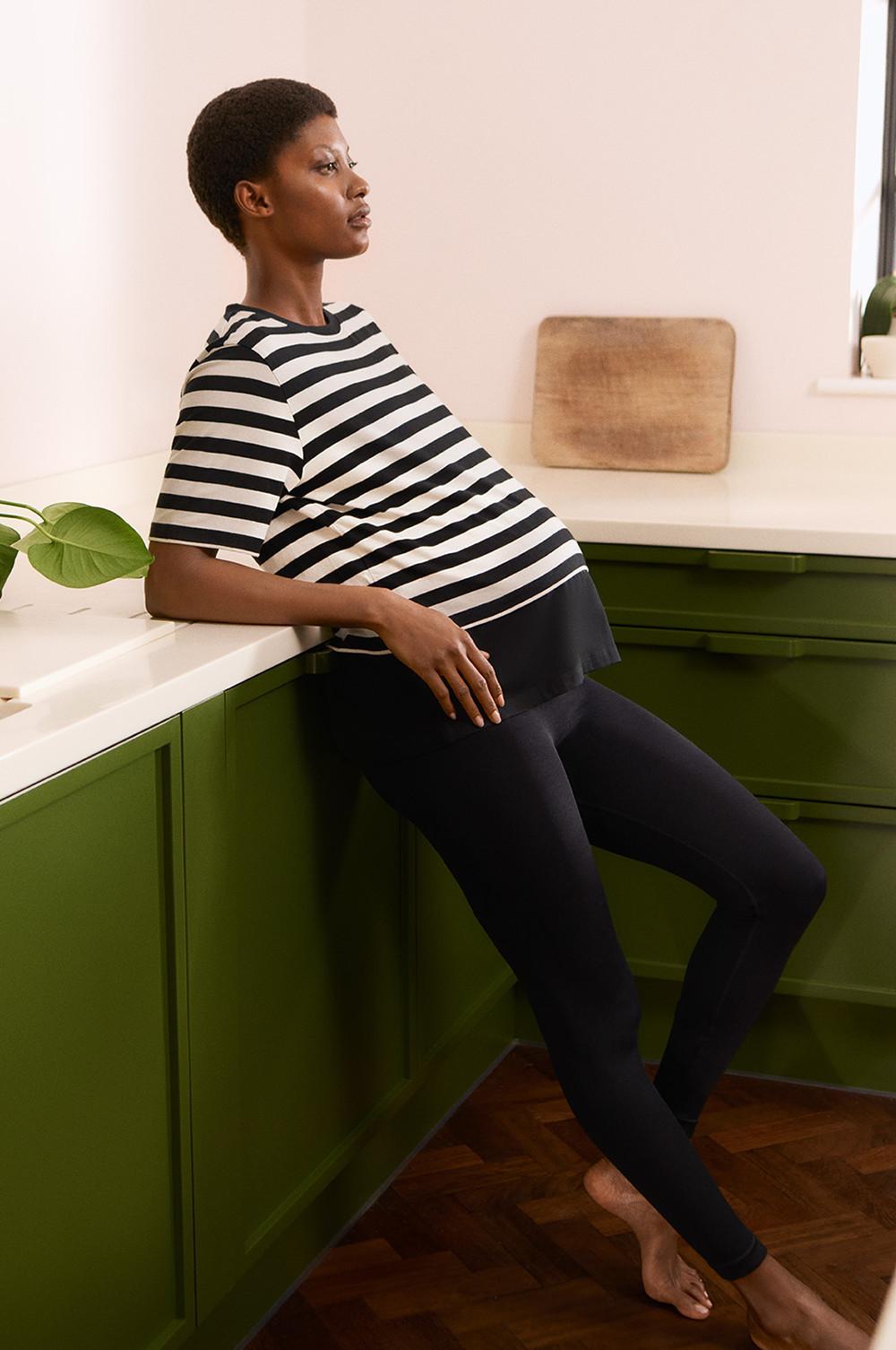 Mannequin portant un t-shirt de grossesse rayé noir et blanc et un legging de grossesse noir.
