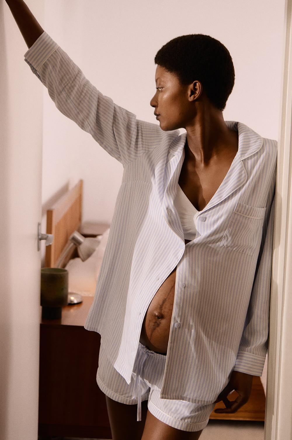 Mannequin portant un soutien-gorge en coton blanc avec une chemise de pyjama à manches longues et rayures grises et un short à rayures grises assorti.