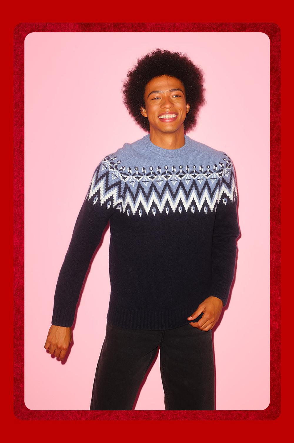 Persona che indossa un maglione blu navy con motivo Fair Isle geometrico blu su sfondo rosa.