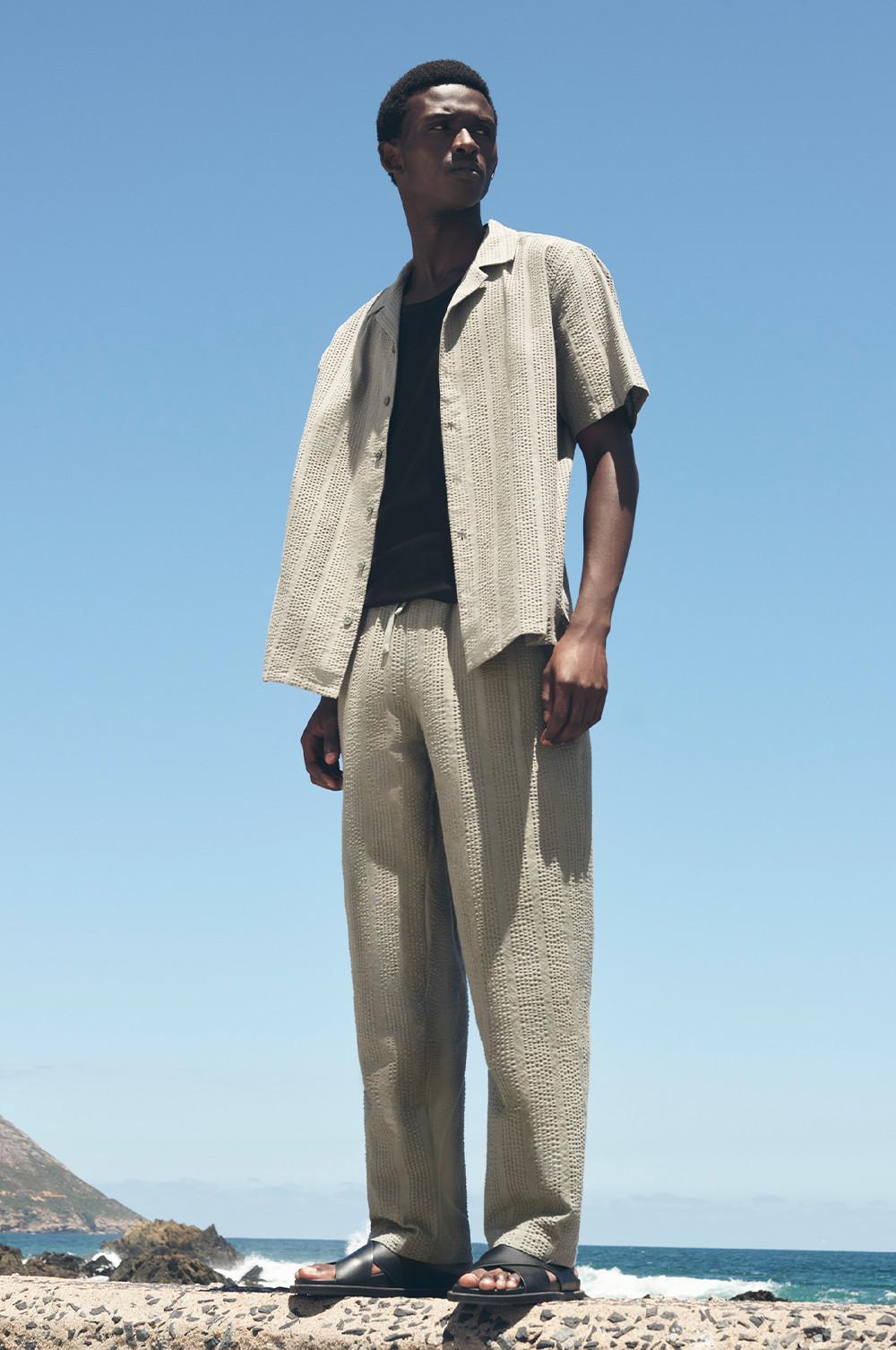 Model wearing a white shirt and grey trousers
