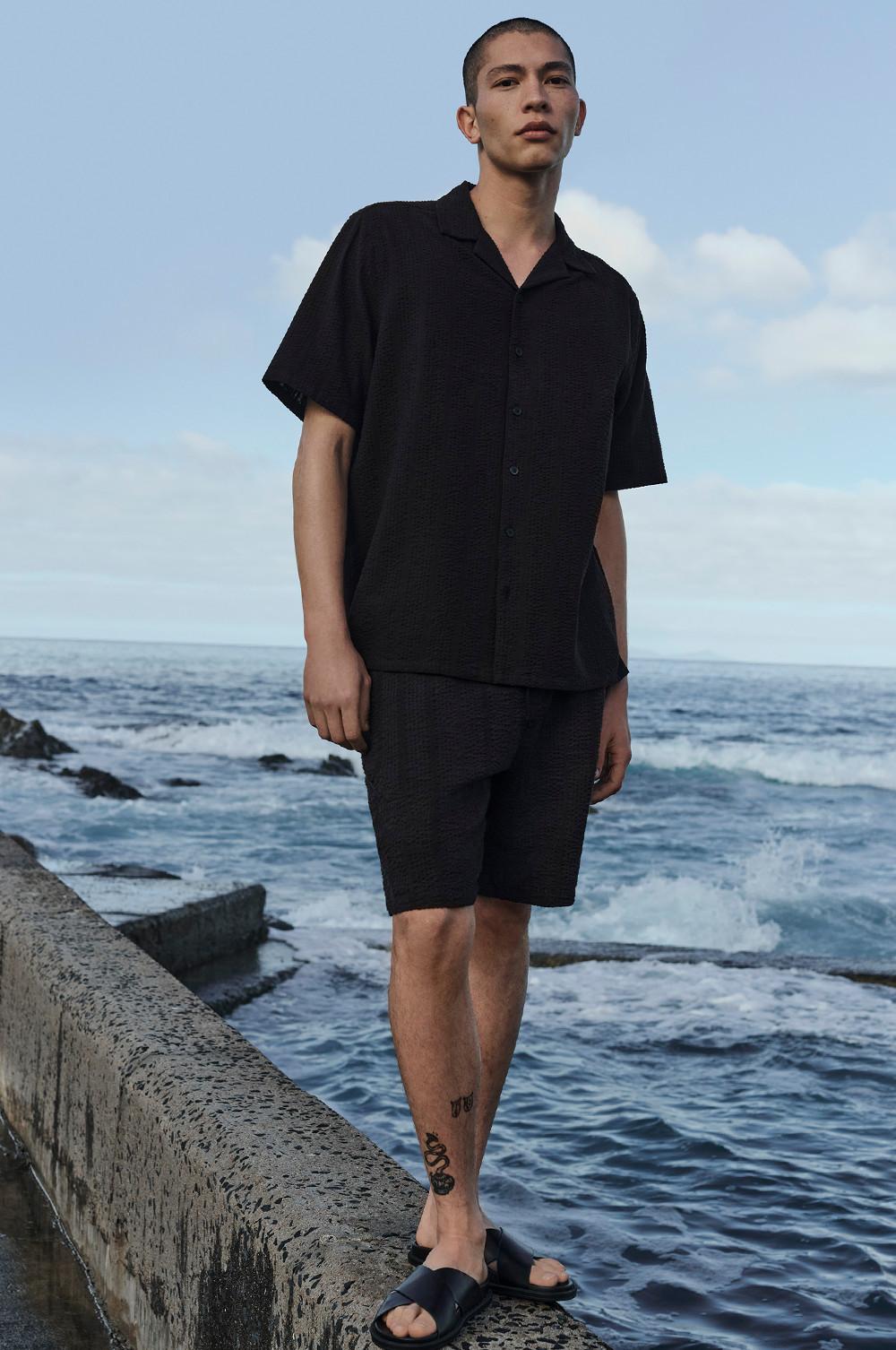 Model wearing black shirt and shorts co-ord set