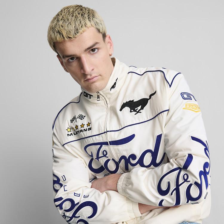 model wearing a white Ford Mustang racing jacket with blue graphics and logos, arms crossed.