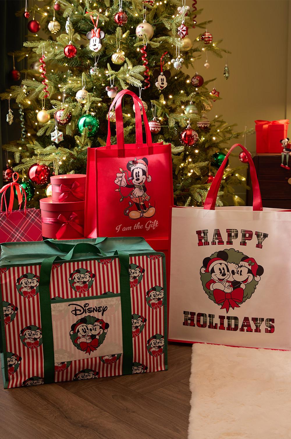 Disney Christmas gift bags and packages displayed in front of a decorated tree with Mickey Mouse ornaments.