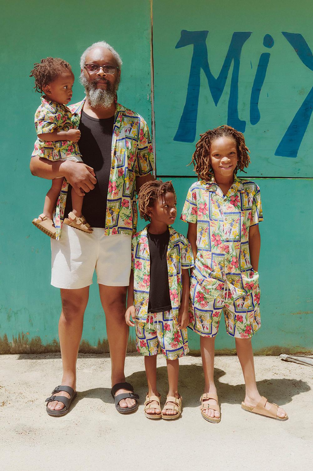 Famiglia composta da un adulto e tre bambini, tutti con camicie a fantasia floreale abbinate. Bambini che indossano pantaloncini floreali abbinati e sandali color cuoio, e adulto che indossa pantaloncini bianchi e sandali neri