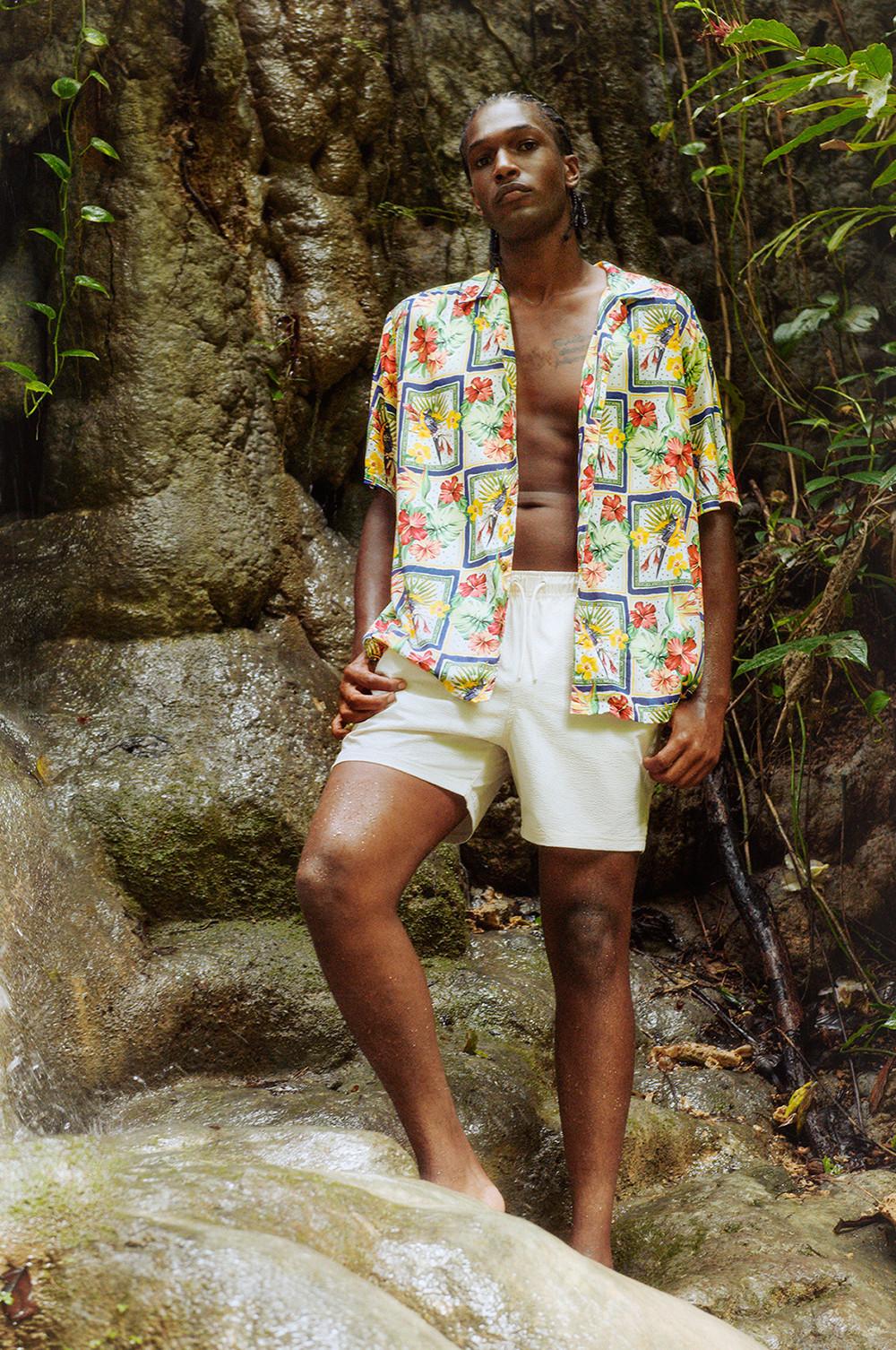 Modello che indossa una camicia tropicale a fiori e pantaloncini bianchi con coulisse