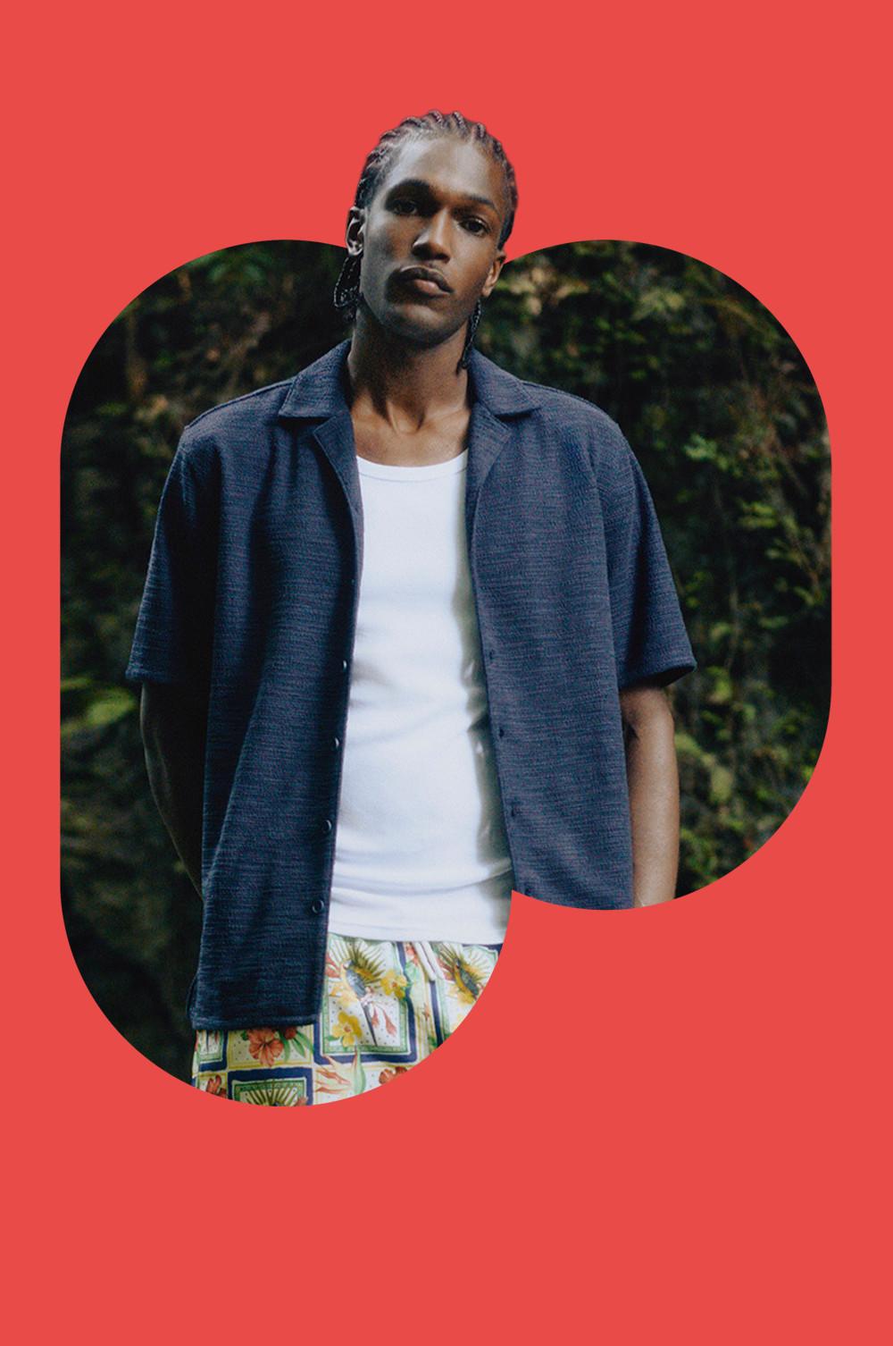 Modello che indossa una camicia blu navy su una maglietta bianca e pantaloncini con stampa a fiori tropicali