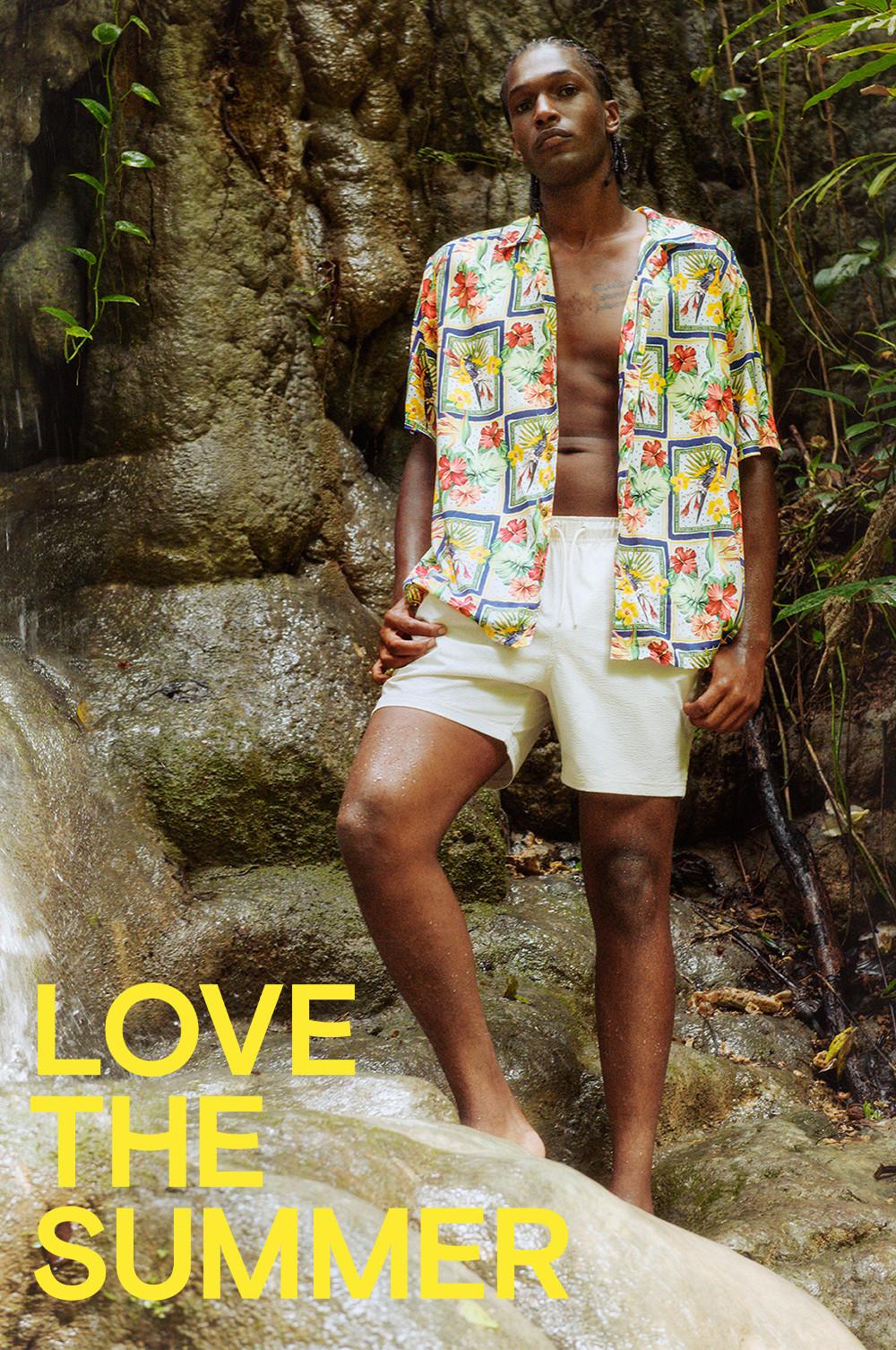 Model wearing tropical floral shirt with white drawstring shorts.