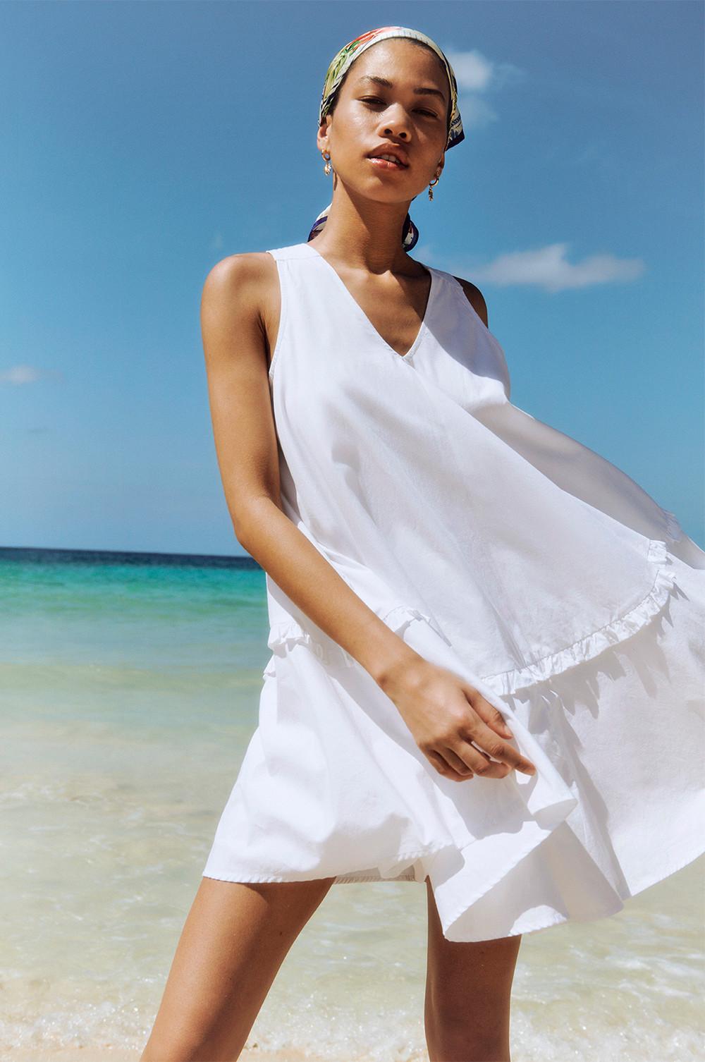 Modelo con vestido blanco y el mar de fondo.