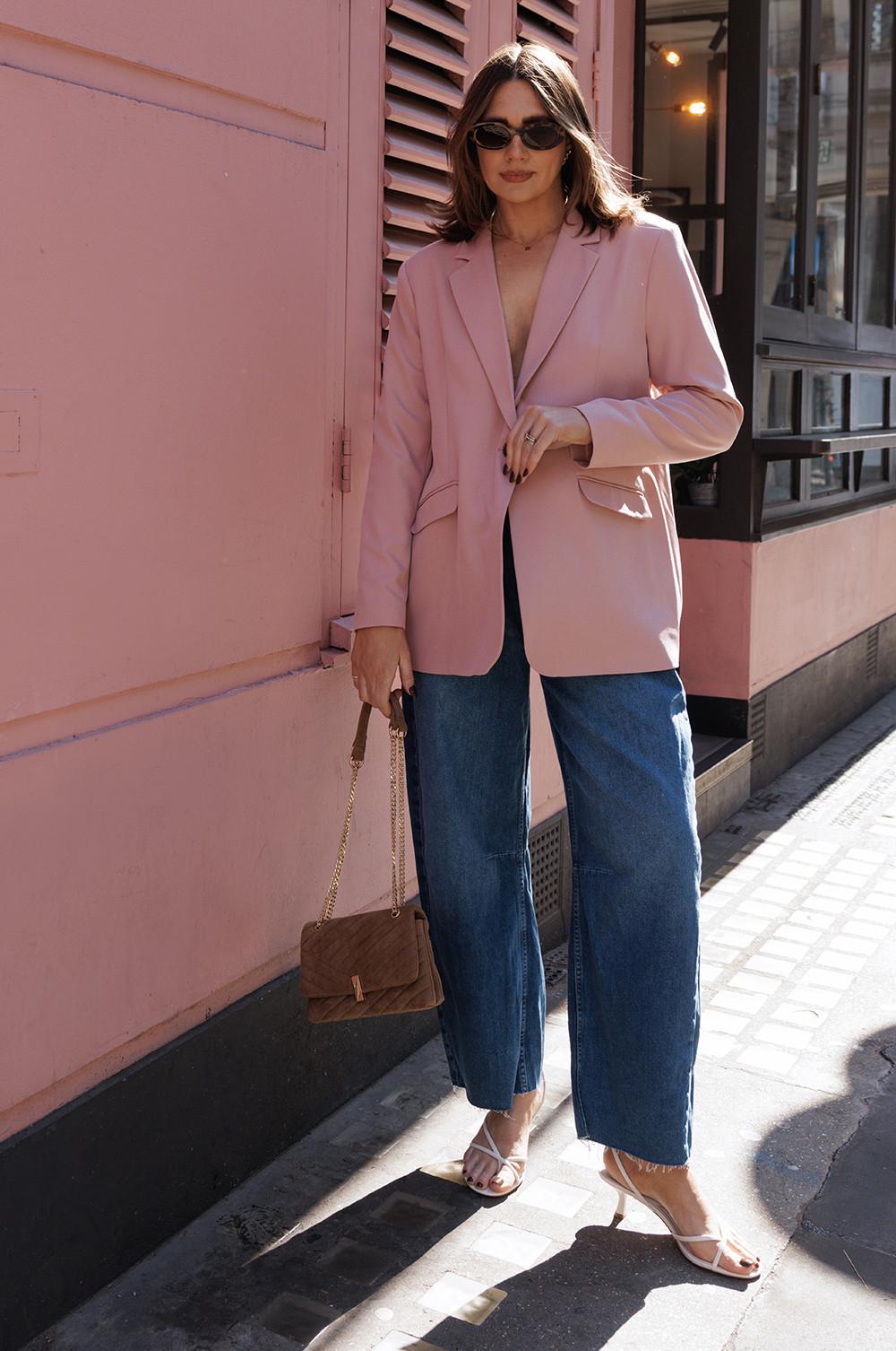 Model wearing sunglasses, blue jeans, pink heels and pink blazer