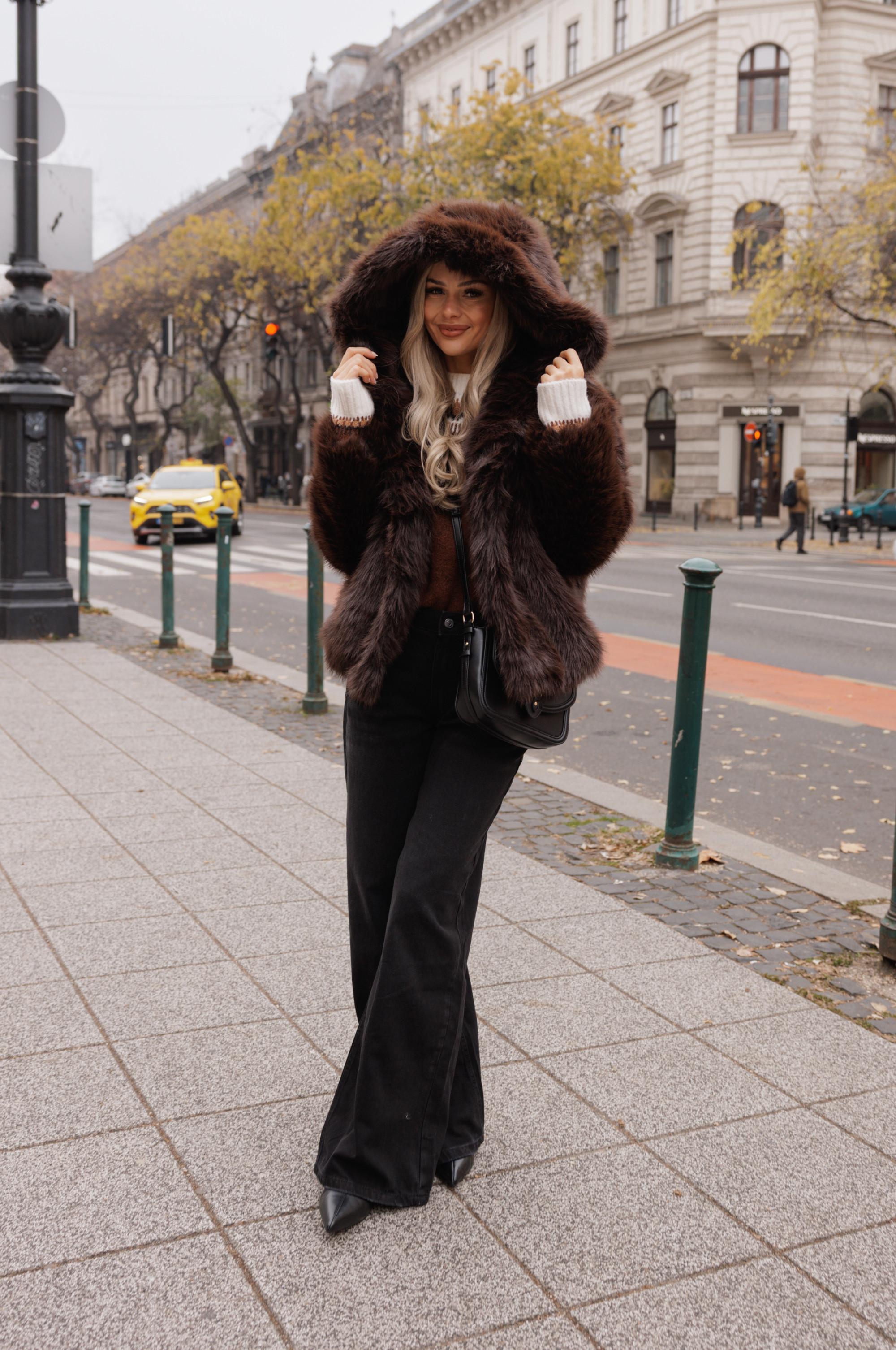 Brown faux fur hooded coat worn with black wide-leg trousers and small handbag on a city street.