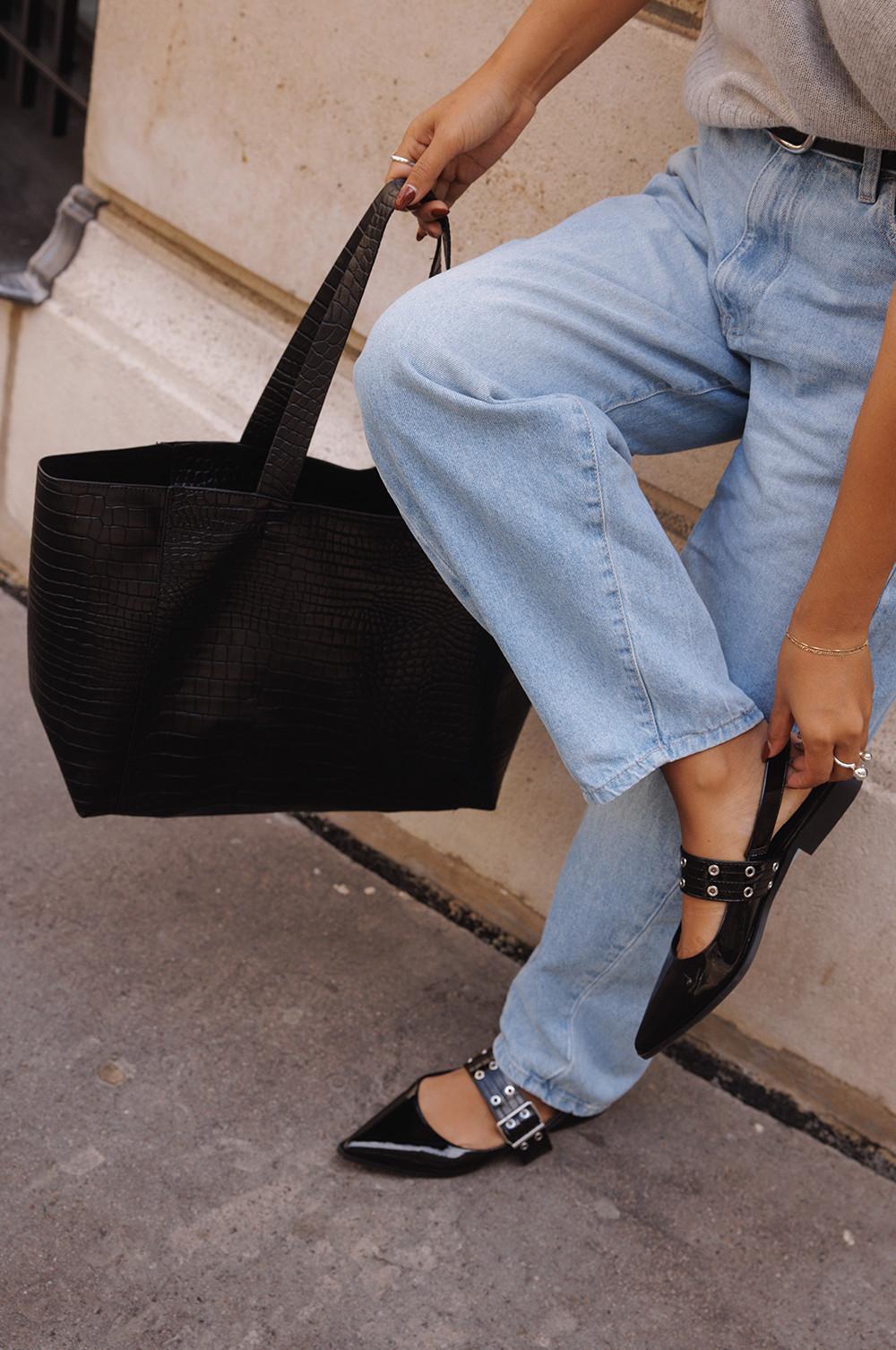 Donna che indossa blue jeans, ballerine nere e una borsa tote nera