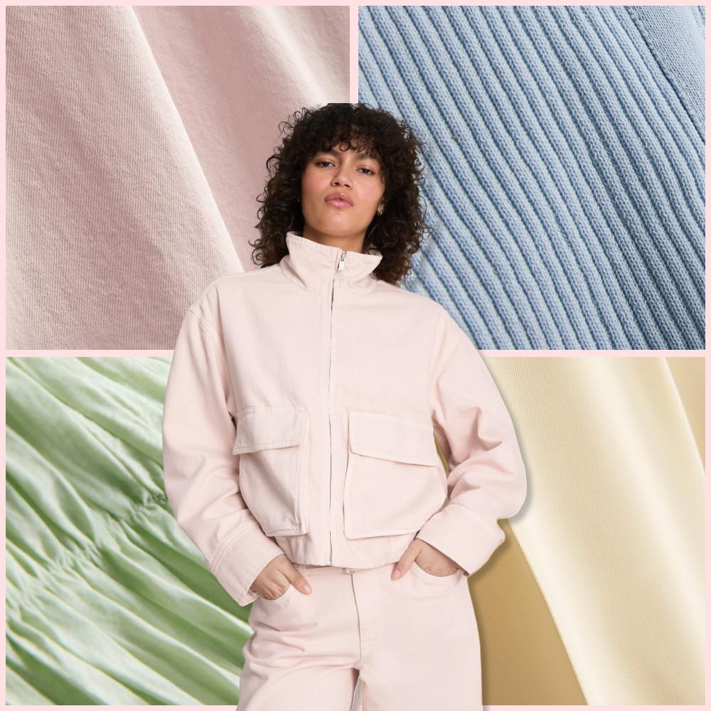 Person wearing pale pink utility jacket with front pockets and matching pants against colorful fabric backdrop.