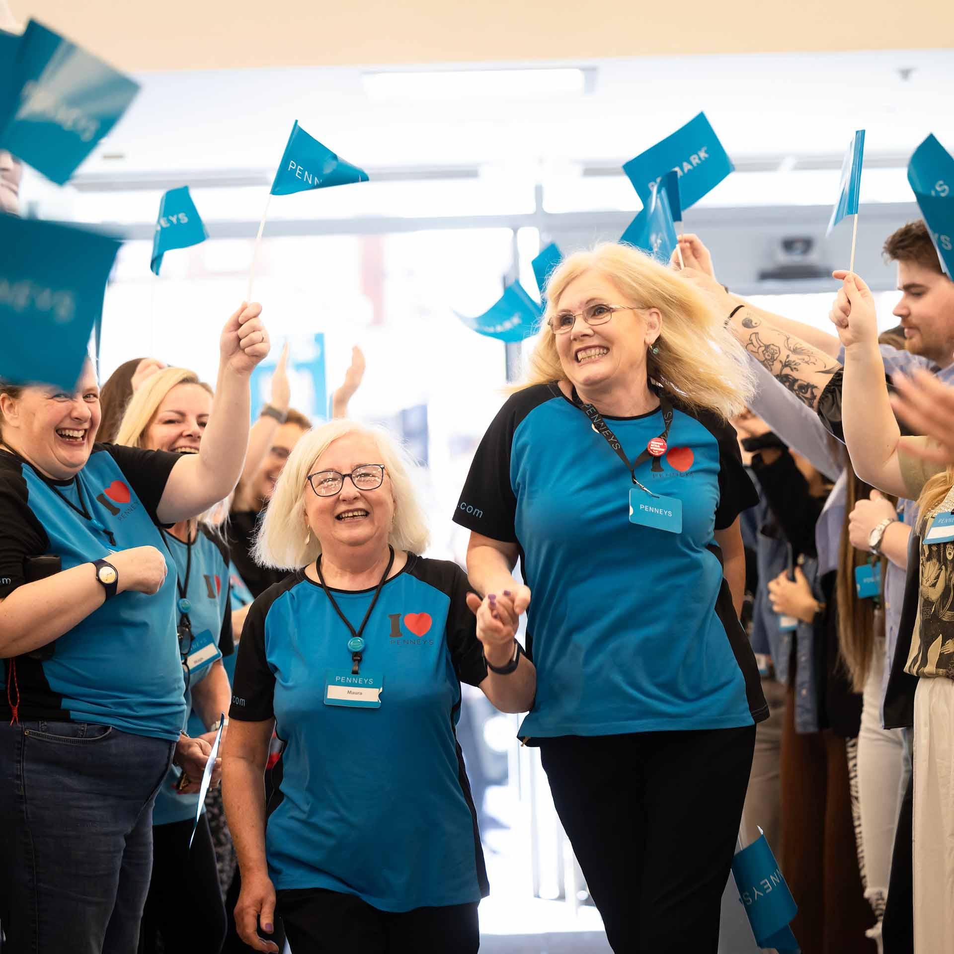 Smiling Penneys employees walking through the refitted O'Connell Street store and waving flags.