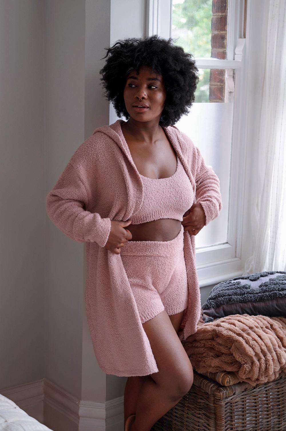 Model in set van een roze teddy top, korte broek en vest
