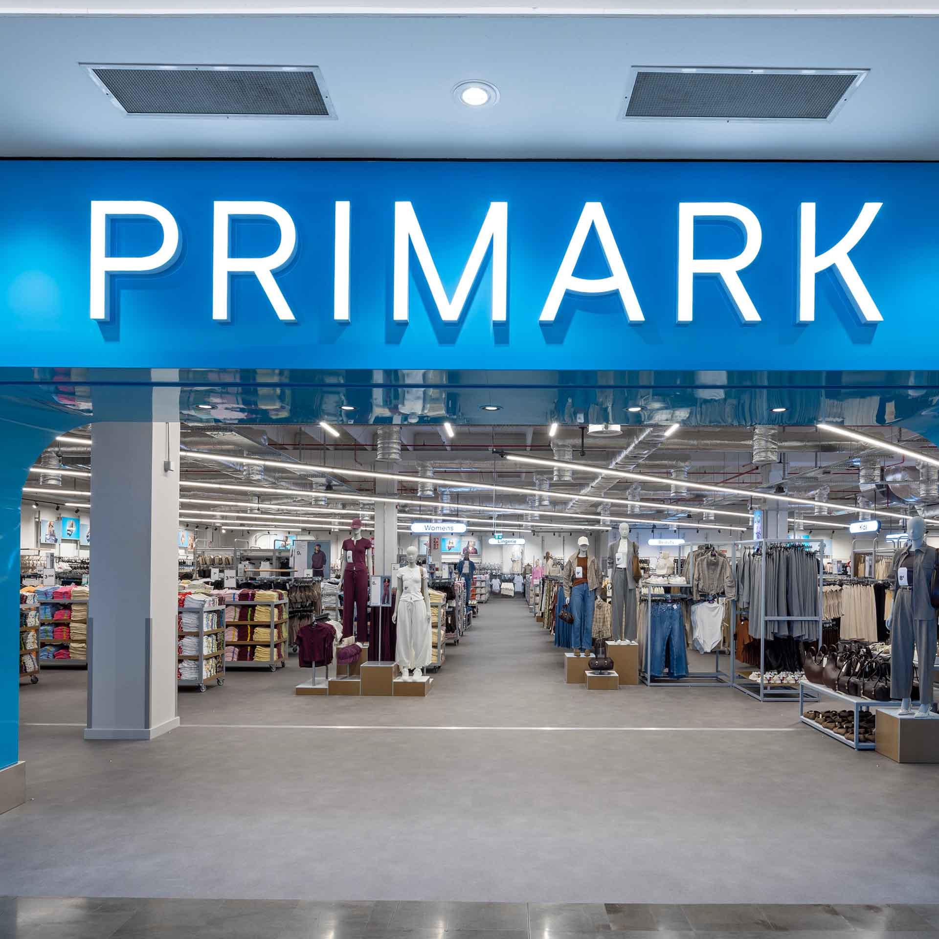 The storefront of a Primark shop with a large, bright blue archway and white illuminated lettering.