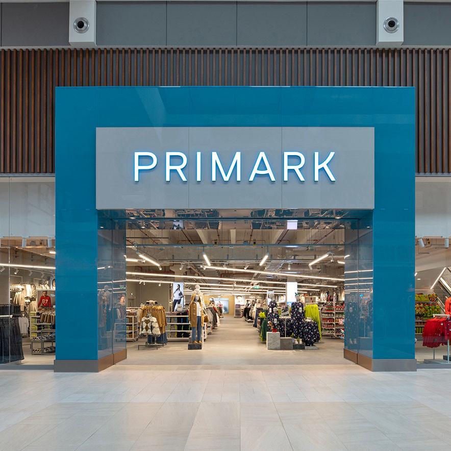 Storefront with 'Primark' in bold letters on a blue facade. The entrance reveals a bright interior.