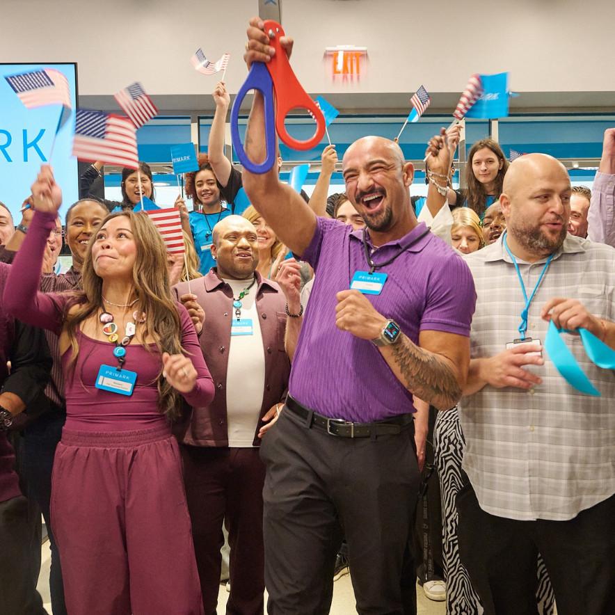 Group of Primark colleagues celebrate the new store opening in Mall of America, waving flags.
