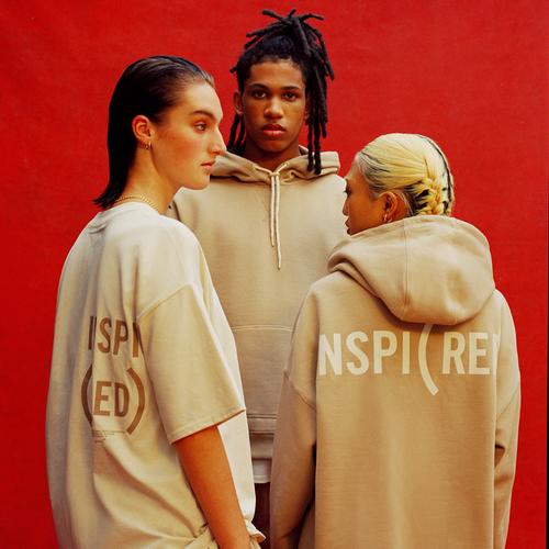 Modellen dragen beige hoodies en T-shirts uit de RED-collectie