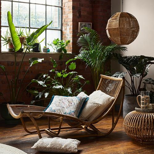 Zdjęcie wnętrza z poduszkami, ratanem i sztucznymi roślinami