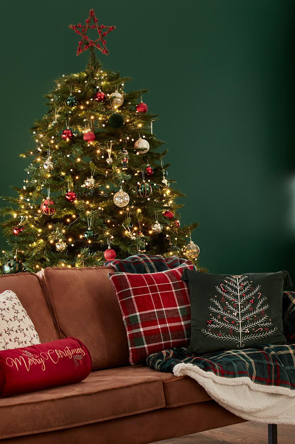Weihnachtliche Wohnzimmereinrichtung mit festlichen Kissen und Schottenkaroüberwürfen