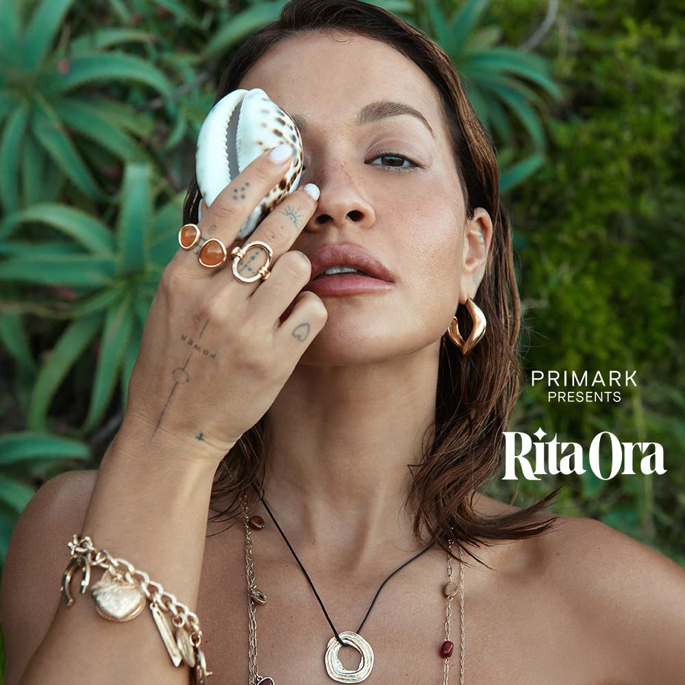 Rita Ora luciendo bisutería variada, sostiene una caracola sobre su ojo derecho