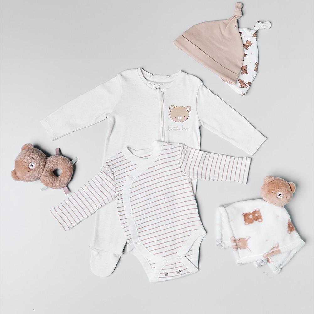 Baby-Kleidungsset mit Stramplern mit Bärenmotiv, Mützen mit Knoten und Plüschtieren in neutralen Beige- und Weißtönen.