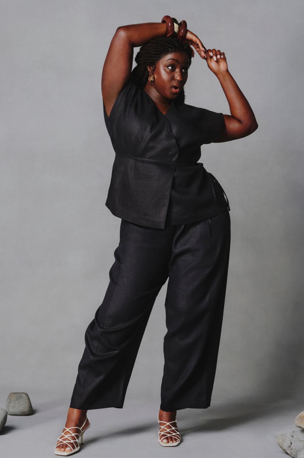 Modelo posando en actitud despreocupada con un conjunto de lino negro compuesto por un top cruzado y unos pantalones de pernera ancha.