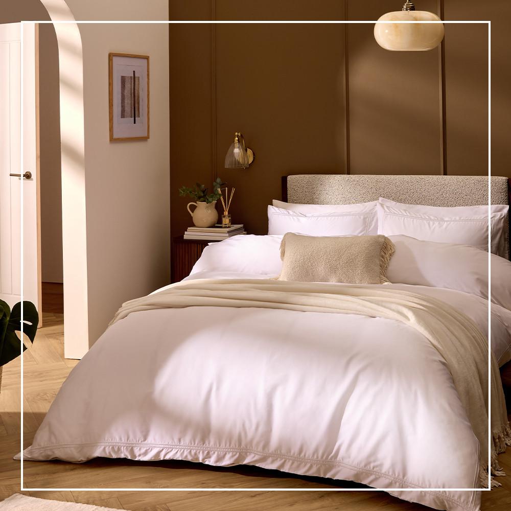 Camera da letto con biancheria da letto bianca, cuscini bianchi e un cuscino panna