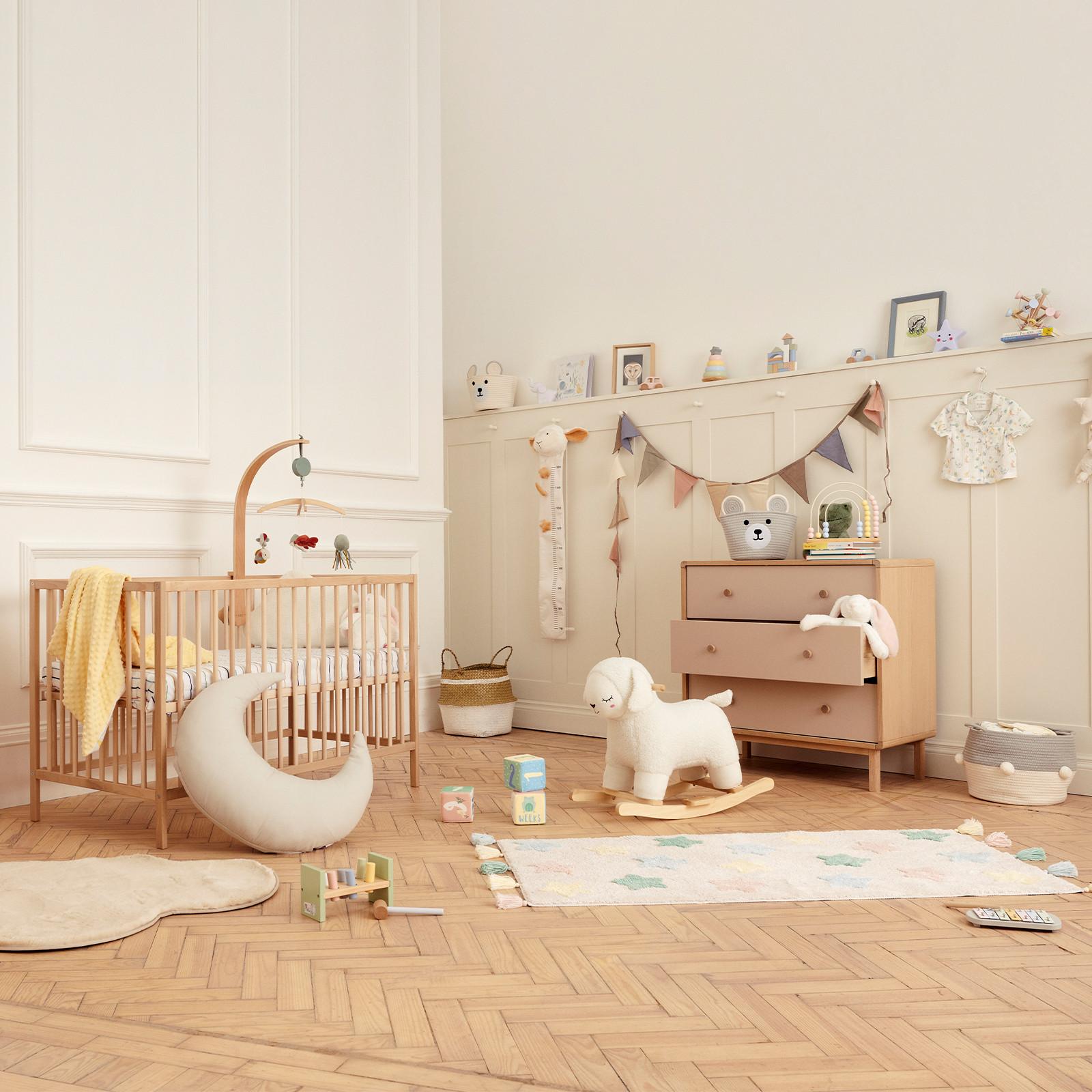 Déco chambre de bébé avec berceau en bois, tiroirs, tapis, jouets et paniers de rangement