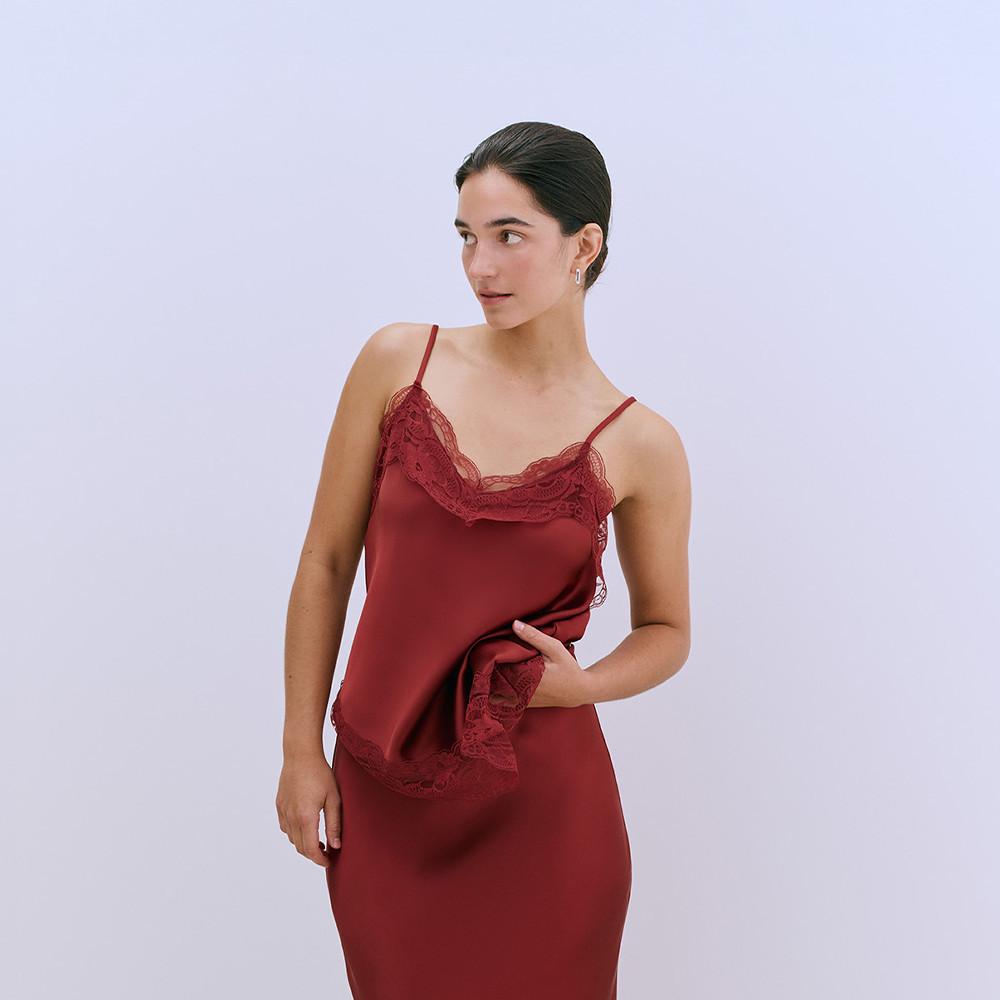 Burgundy slip cami top and matching skirt with delicate lace trim at neckline and hem, showcased on model against white backdrop.