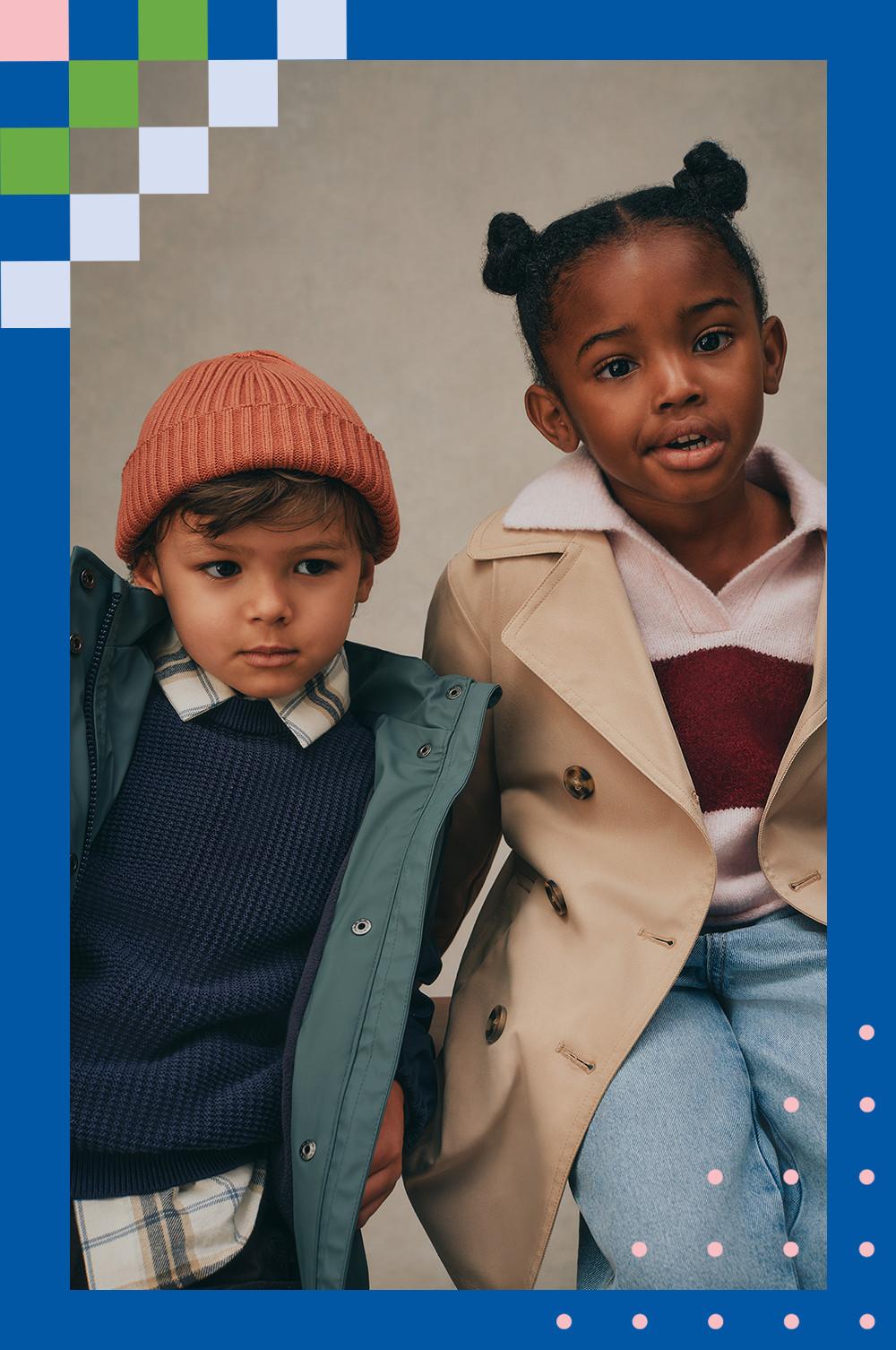 Two children wearing stylish fall outerwear - one in a beanie and green jacket, another in a beige trench coat with burgundy sweater.