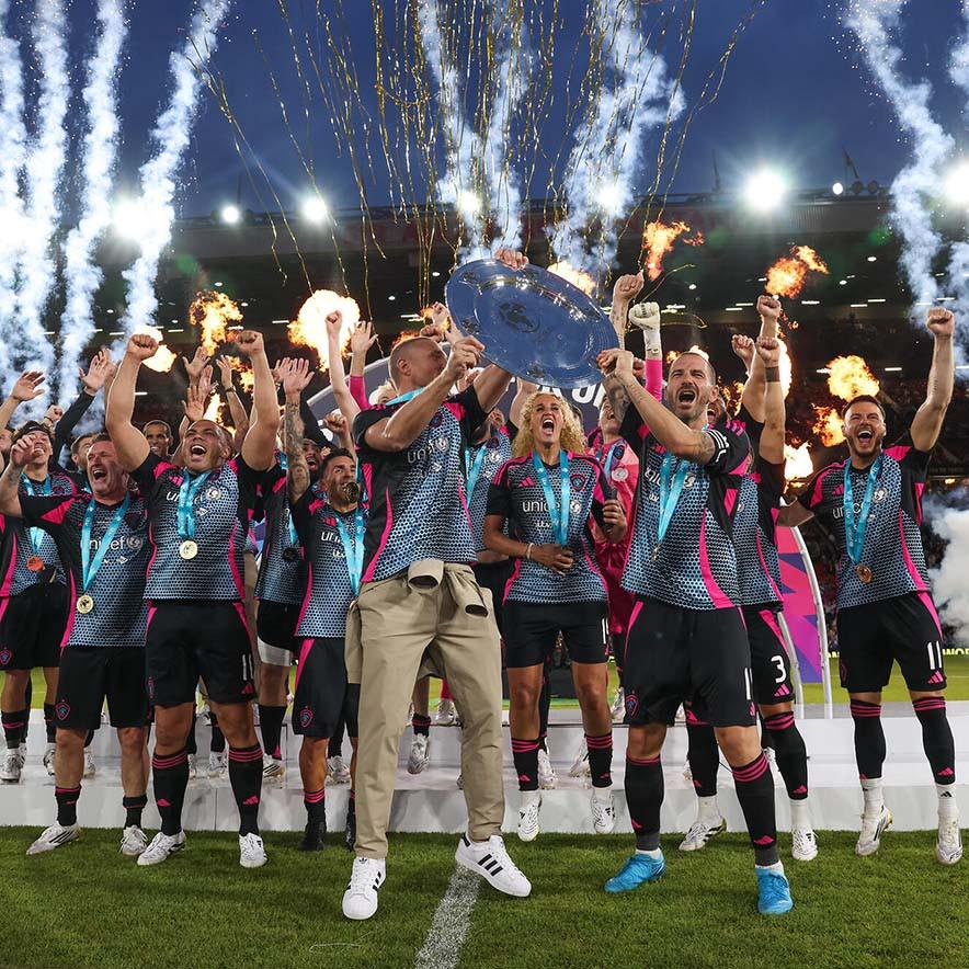 Soccer team celebrates victory under fireworks, lifting a trophy.