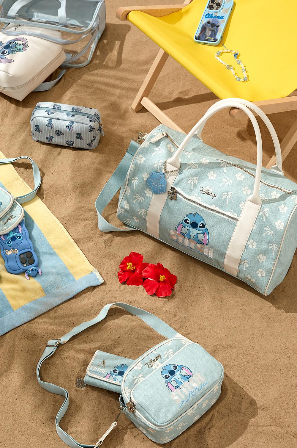 Stitch travel accessories such as a duffle bags, crossbody pouches, toiletry organisers, phones cases and beach towel displaying on a beach