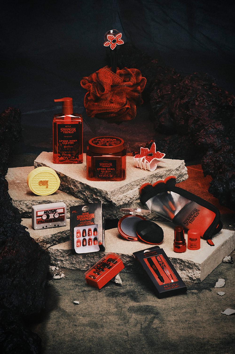 Collection of Stranger Things themed beauty products including cleansers, makeup and accessories on stone platforms.