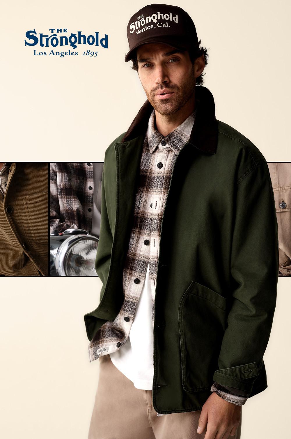 Persona che indossa una giacca verde, una camicia con motivo scozzese e berretto The Stronghold. Con logo all'angolo.