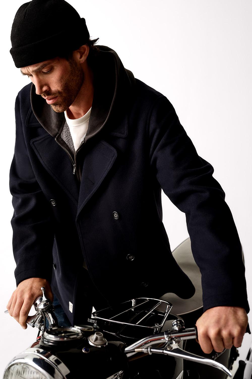 Black winter coat with sherpa-lined hood worn over a dark hoodie with partially visible burgundy layer.