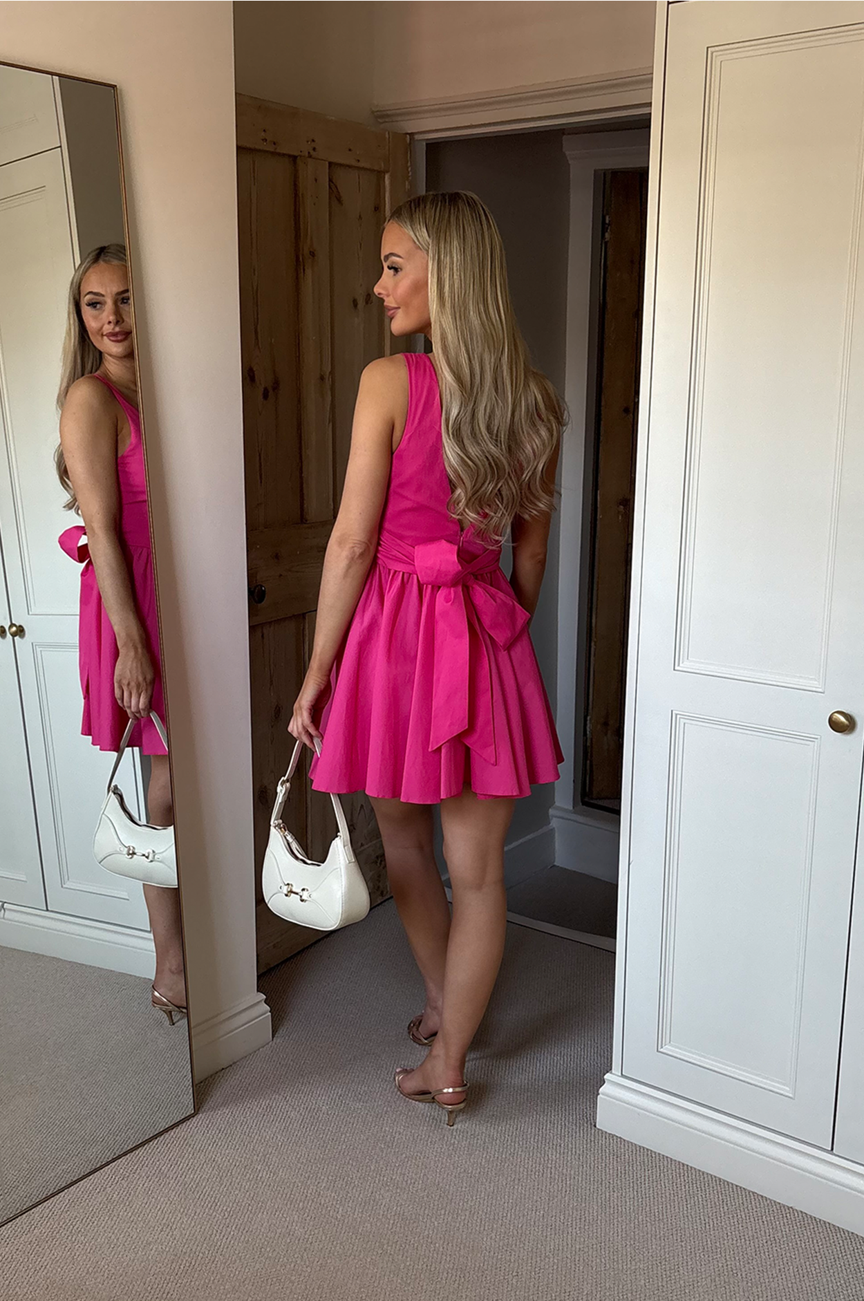 Model wearing midi corset sleeveless dress in pink with a white bag